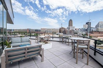 A rooftop patio with a table and chairs overlooking a city skyline.